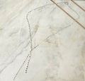 Silver lariat necklace on a marble surface