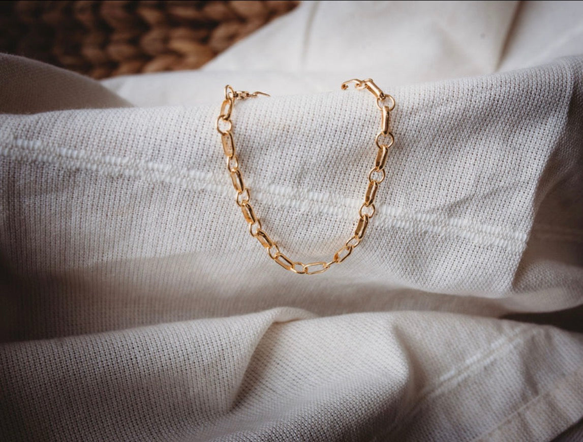 Gold chain bracelet on a textured fabric surface