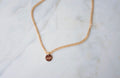 Thick Gold chain necklace with a  mama round tag on a marble surface