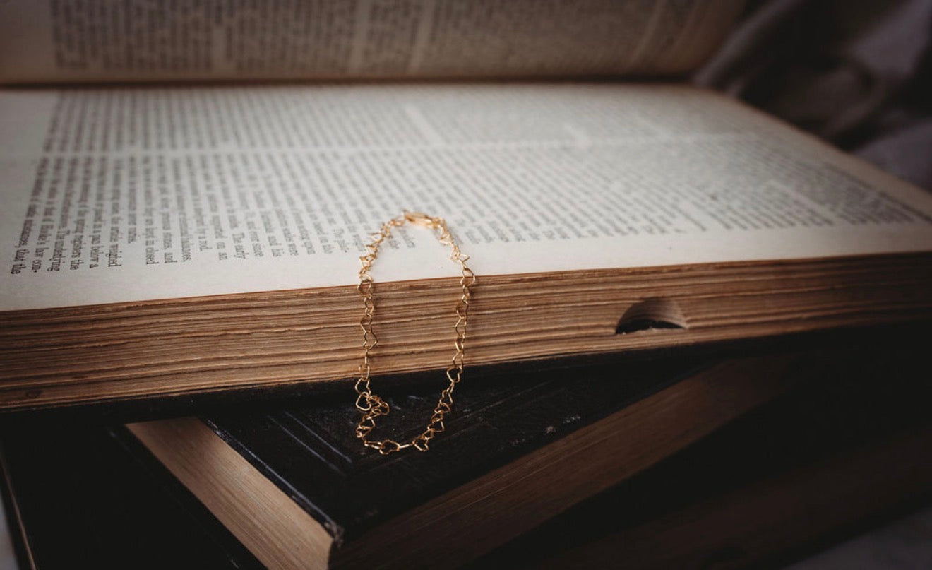 Gold heart bracelet on an open book