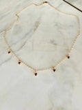 Gold necklace with 5 heart-shaped pendants on a marble surface