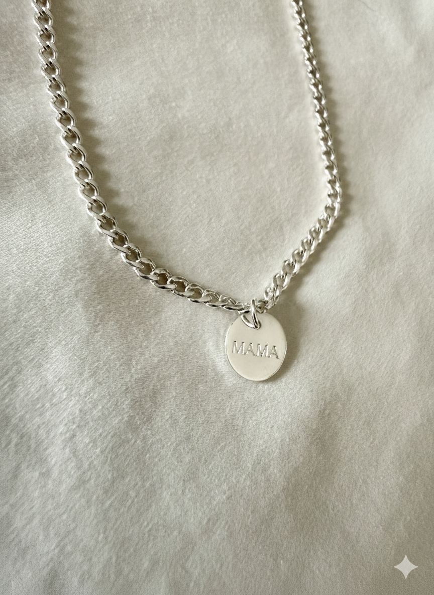 Thick Silver chain necklace with a round mama tag on a light gray background