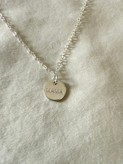 Silver necklace with a 'MAMA' pendant on a light gray background