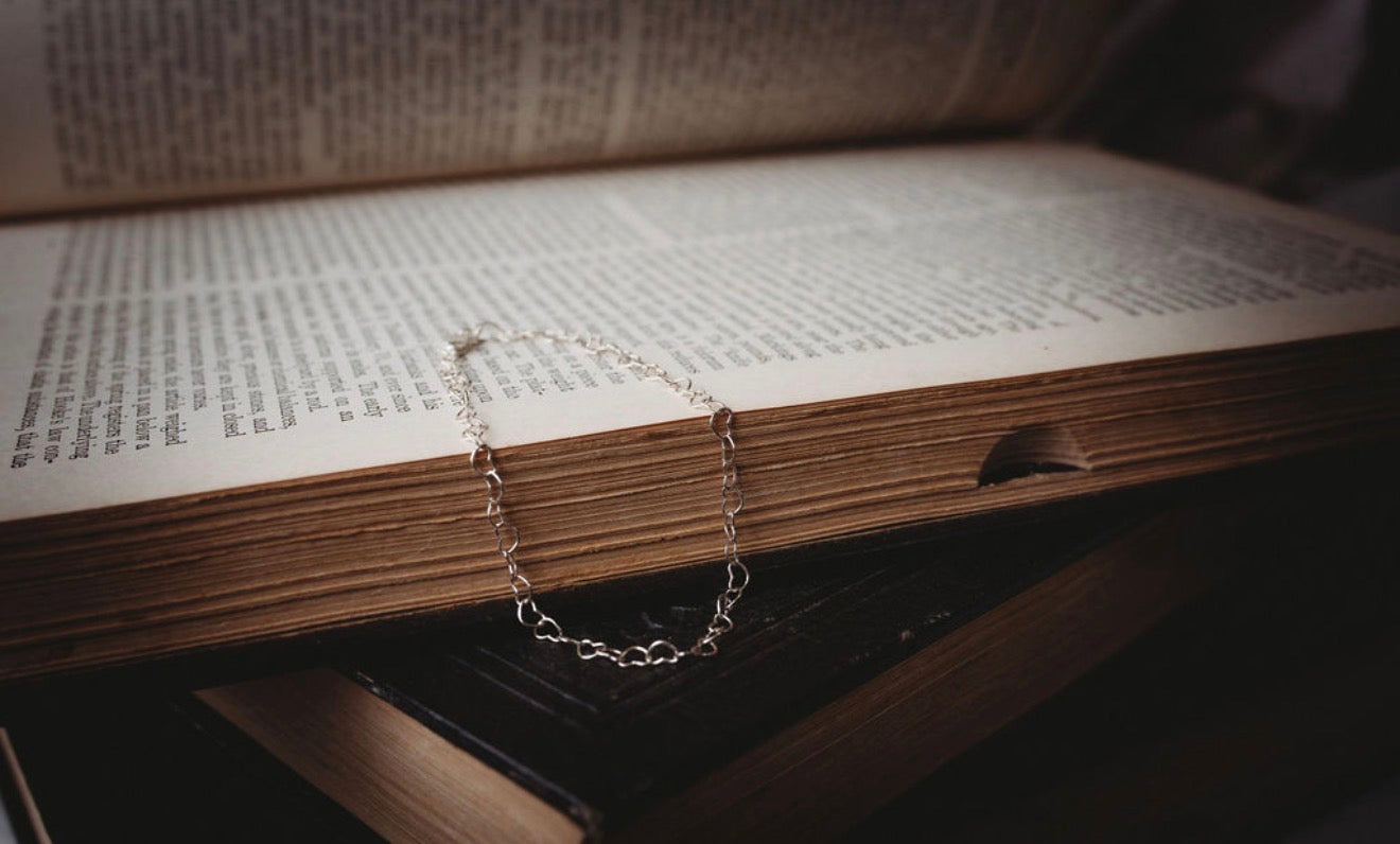 Silver heart chain bracelet on an open book
