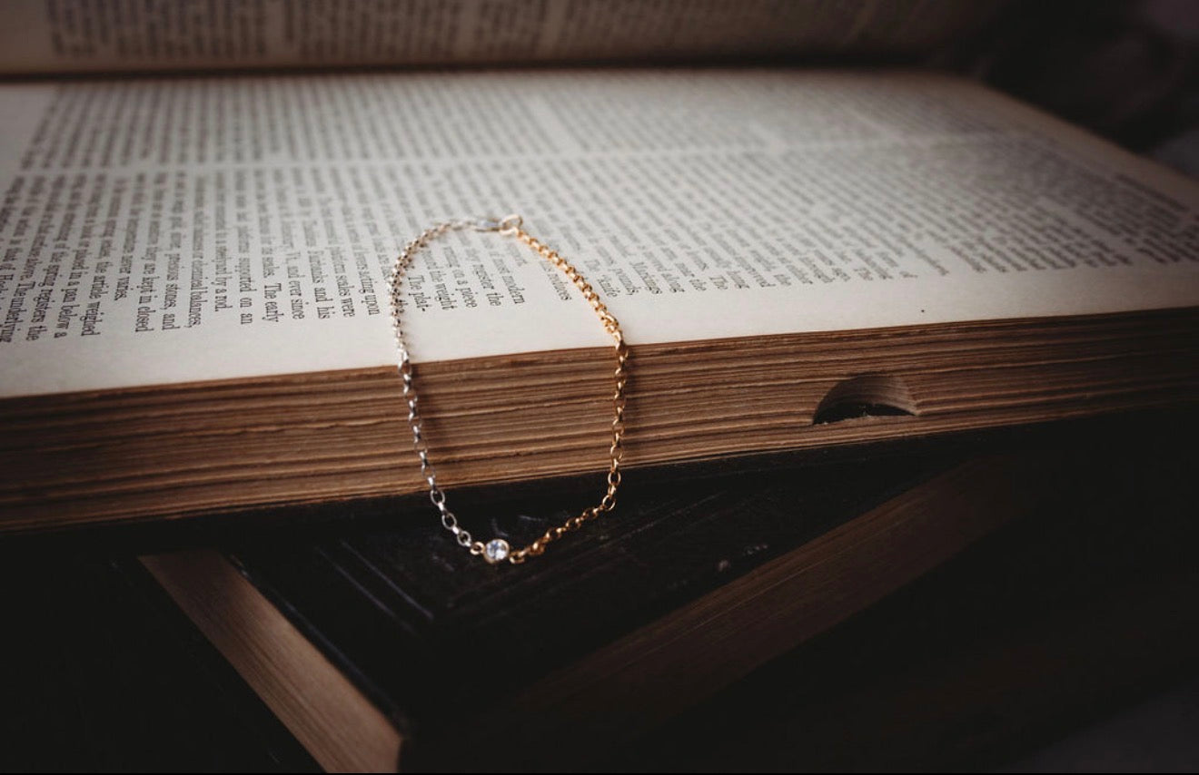 Gold and silver bracelet with diamond in center on an open book